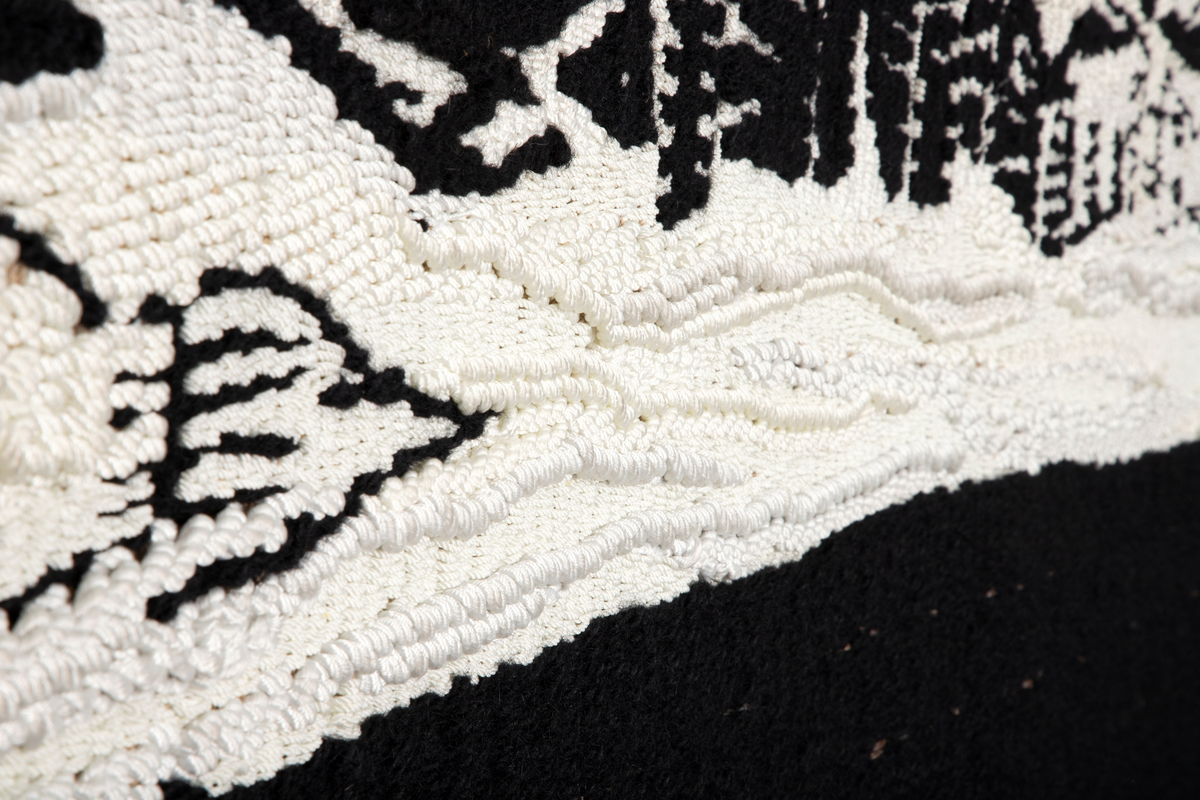Motivet er todelt. Den ene halvdelen i hovedsak sort, den andre er sort hvit med motiv. Motivet viser dyresymboler, stilliserte ansikt og annet fordelt på tre horistonale felt. Motivet danner et mønster med en ornamental og repeterende karakter.