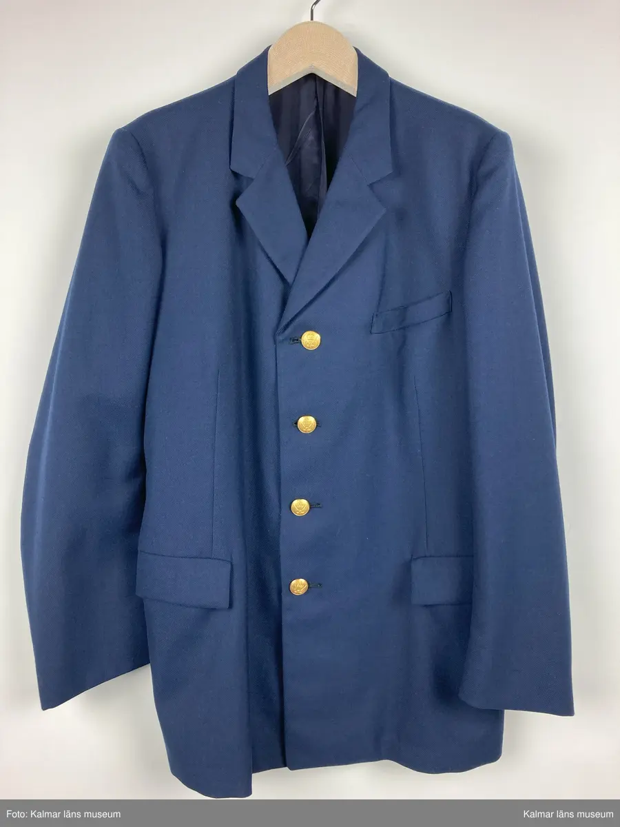 KLM 44463:9. Kavaj. Uniformsjacka för stins, SJ. Storlek C54. Av kypertvävt mörkblått ylle. Krage och slag. Knäpps fram med fyra st. knappar av gulmetall med SJ vapen på. Fickor med ficklock samt bröstficka, på vänster framstycke. Fodrad med mörkblått tyg i livet och grått i ärmen. Hank i nacken. Innerfickor på båda framstyckena. Textiletikett vid höger innerficka med vävd text: CBV C54 KARLSKRONA.  
Kavajen är av tunnare sort och har ev. använts som sommar kavaj till byxor KLM 44463:8:2 och väst KLM 44463:8:3.