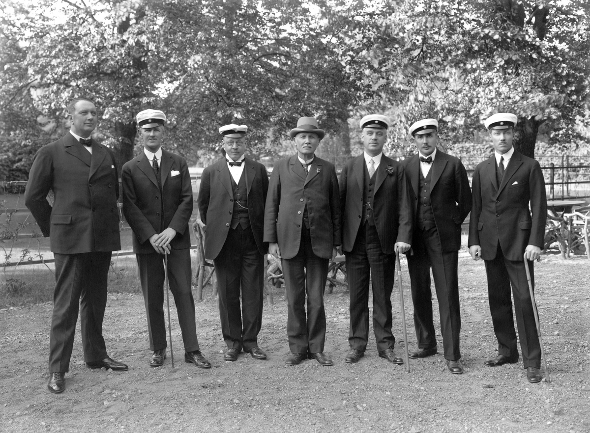 Studentjubilarer från Linköpings högre allmänna läroverk samlade för fotografering. Sannolikt 1924 och 25-årsjubileum av examen. Från vänster ser vi Alvar Drangel, Arvid Kugelberg, Johan Skog, lektor Bernhard Risberg, Herman Samuelsson, Valter Mårtensson och Eskil Ridderstad.