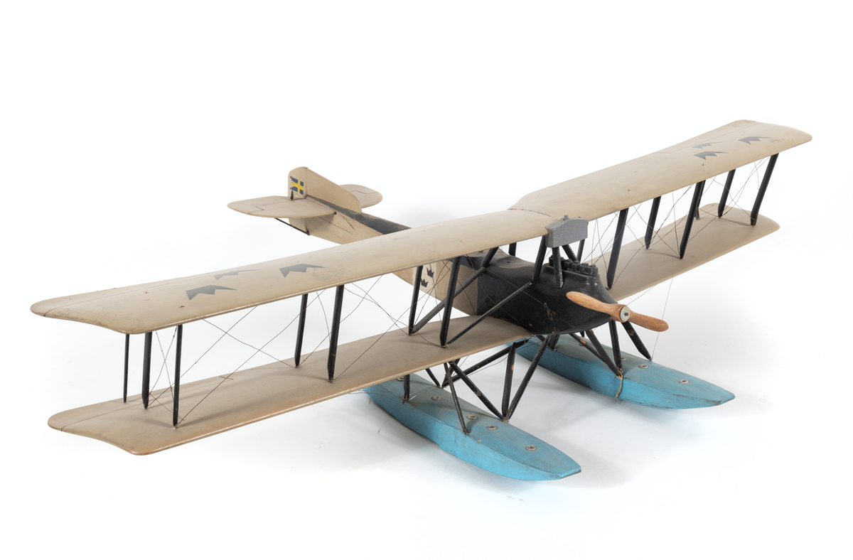 Modell av flygplan, Friedrichshafen FF 49. Enmotorigt biplan, två flottörer. Inbyggd flygkropp mellan vingarna. Smala, långa vingar, lika stora, bredare akterkant. Två horisontala roder på den övre. Stjärt med halvcirkelformad bäryta, två horisontala och ett vertikalt roder. Stöttor och stag av metall.

Gråmålat. Sittrum och flygkroppens översida svarta, flottörer blå. Tre svarta kronor på vingar och flygkropp. Svensk örlogsflagg på vertikalrodret.