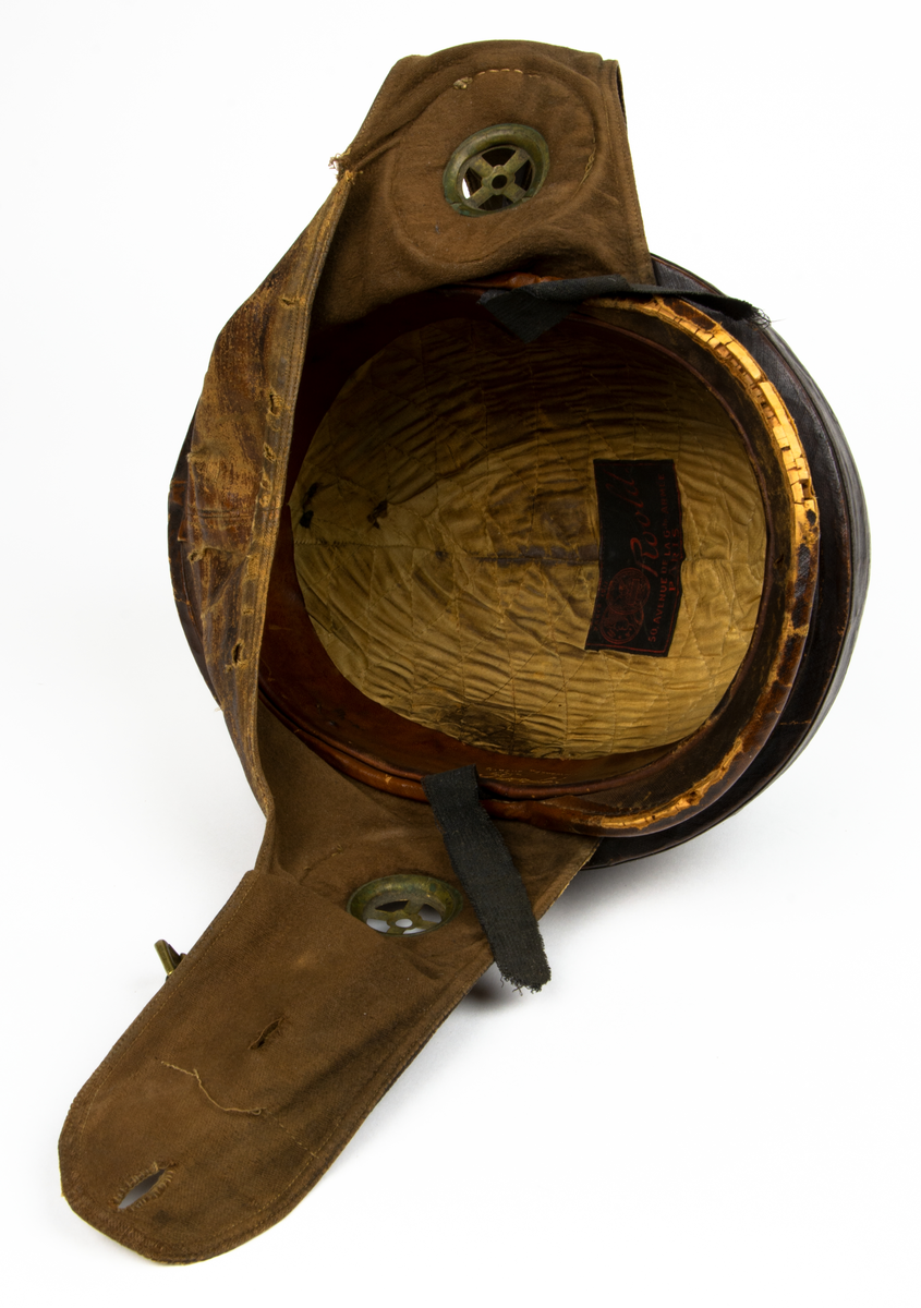 Flyghjälm av äldre model,l även kallad störthjälm eller störtpralin. På insidan texten: "Casque Protecteur Roold, BREVETÉ S.G.D.G."
På insidan en liten rund etikett med siffran 60.