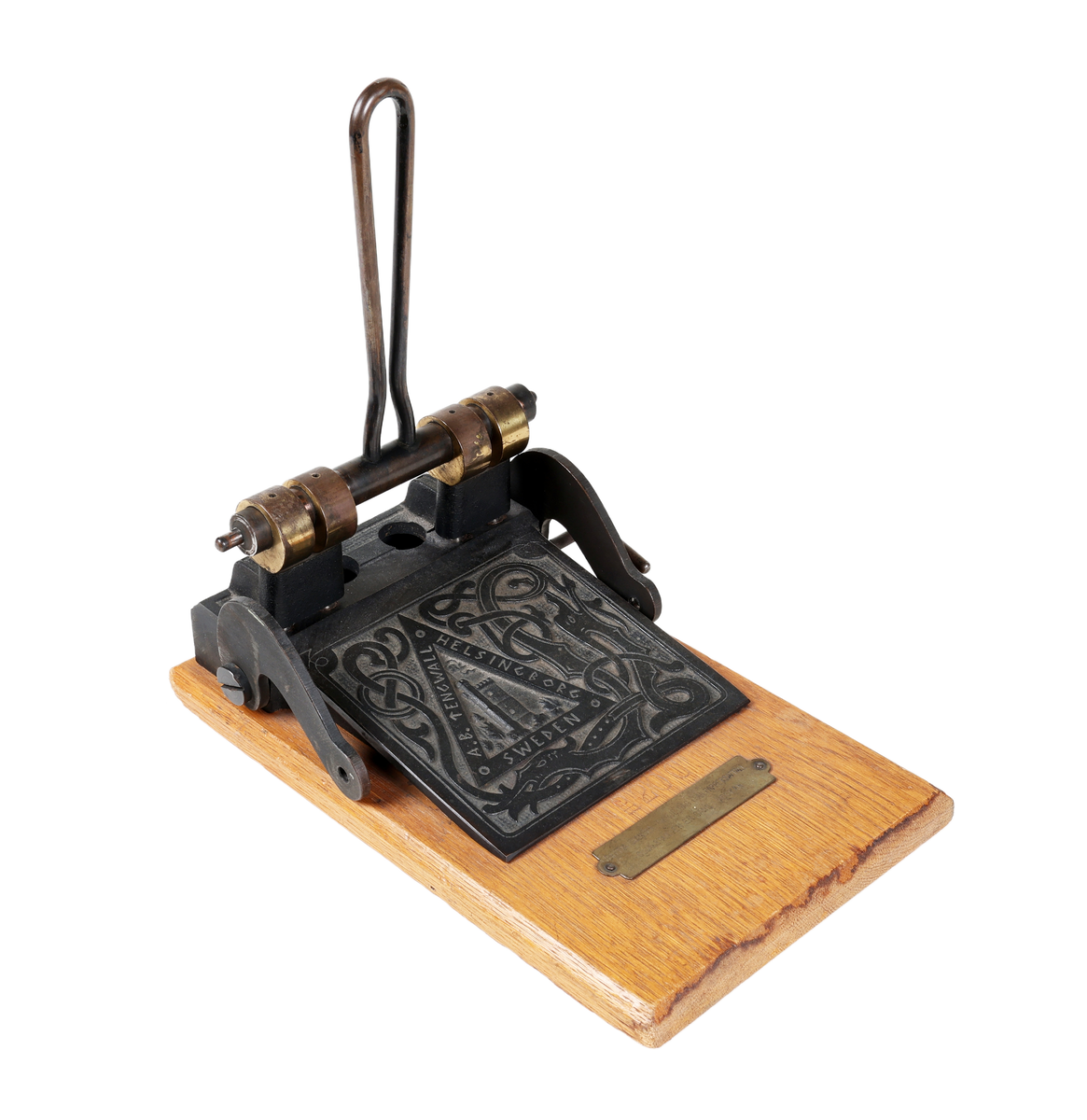 Hålstans med reliefdekor föreställande "fästningen kärnan" inom triangel och omgiven av drakslingor. Styrskena för olika pappersstorlekar. Märkt: A.B. TENGWALL HELSINGBORG SWEDEN No 200. 

Äldre historik:
Kärnan är ett torn som är den enda kvarstående byggnaden av det medeltida Helsingborgs slott. Dendrokronologisk datering har visat att Kärnan byggdes på 1310-talet, då Erik Menved var kung i Danmark. Tornet är 35 meter högt och ligger i sin tur på landborgen. (Wikipedia)

Proveniens: Oscar Jacobson AB, Borås.

Äldre historik:
Oscar Jacobson är ett svenskt herrkonfektionsföretag grundat i Borås 1903 av skräddaren Oscar Jacobson. Oscar Jacobson var VD i företaget fram till 1957 då han efterträddes av sin son Anders Jacobson. Familjen Jacobson sålde 1971 företaget till Sweteco. (Wikipedia)