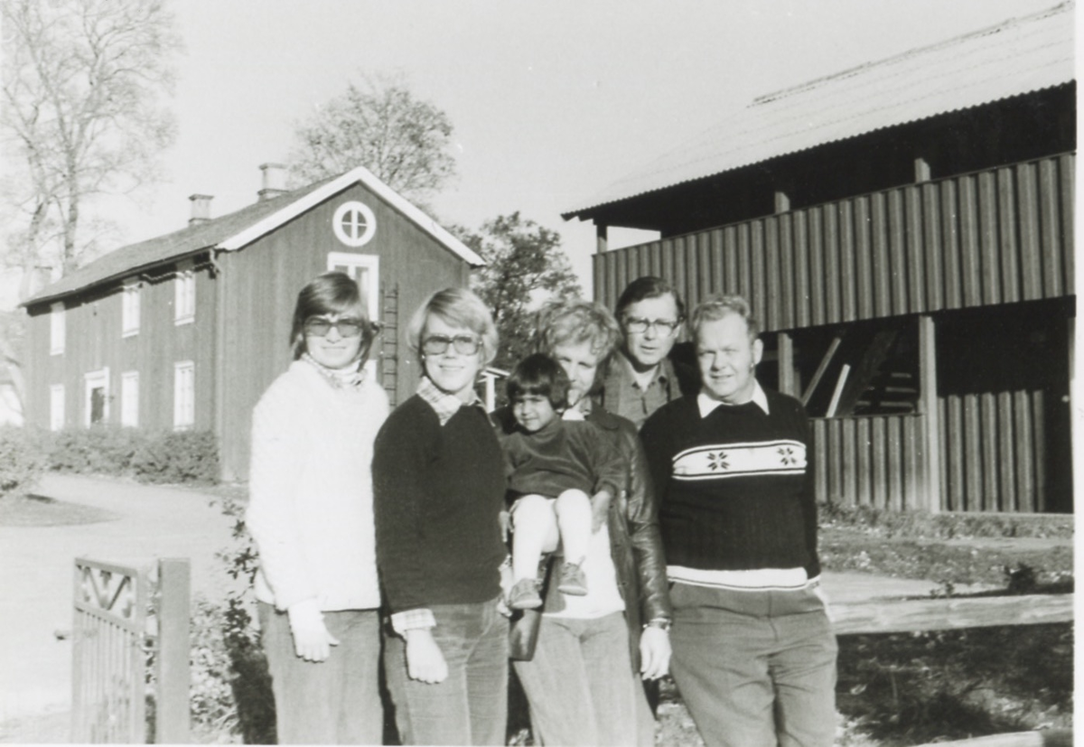 Medföljande vuxna till lägerskola för Brattåsskolans elever åk 6, Ransbergs Herrgård i Värmland 1975. Sex personer står framför två träbyggnader, där elever, föräldrar och lärare övernattade under vistelsen. Från vänster: 1. Ingrid Bergström, förälder. 2. Okänd. 3. Tomas Bergström, lärare med barn i famnen. 4. Rolf Werner, lärare. 5. Okänd.
Relaterade motiv: A4633 - A4637.