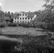 Huvudbyggnaden till Norrby säteri i Sund socken inbäddad i grönska. Byggnaden uppfördes 1840 av major Fredrik Reinhold Rehbinder. Foto 1956.