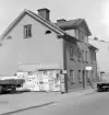 Kungsgatan 27 i Linköping med ett typiskt uttryck för husen utmed gatans mer perifera sträckning i öster. Tomten hitom huset samlade en rad verksamheter, varför 27:ans fasad var lämplig för annonsering. Foto 1965.