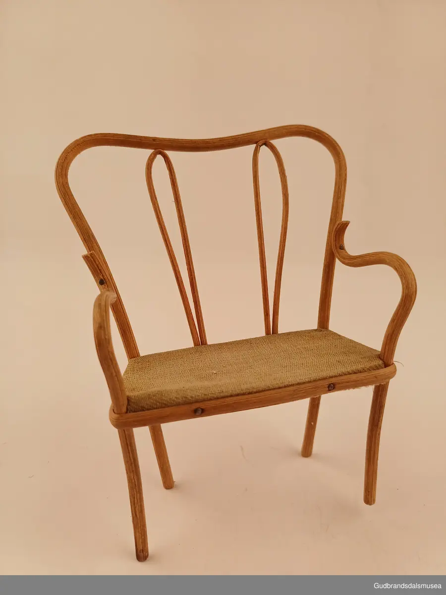 Leke sofa. En del av et sett med 2 stoler til
Buet rygg, spikret til setet med pedding som er lagt utenpå/rundt setekanten. Setet er av furu, trekt med stoff.
Bredde 10 cm
Høyde 14 cm