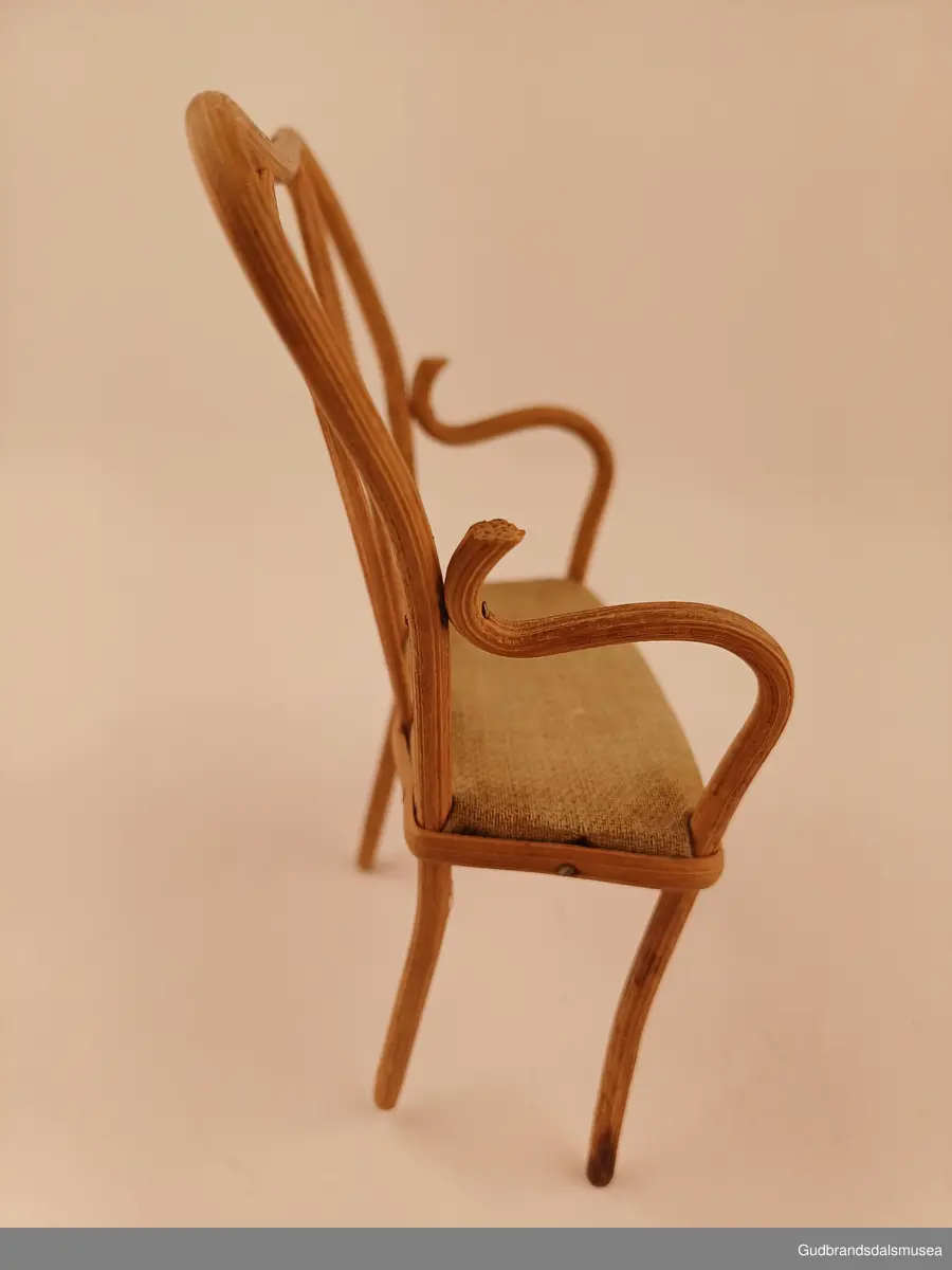 Leke sofa. En del av et sett med 2 stoler til
Buet rygg, spikret til setet med pedding som er lagt utenpå/rundt setekanten. Setet er av furu, trekt med stoff.
Bredde 10 cm
Høyde 14 cm