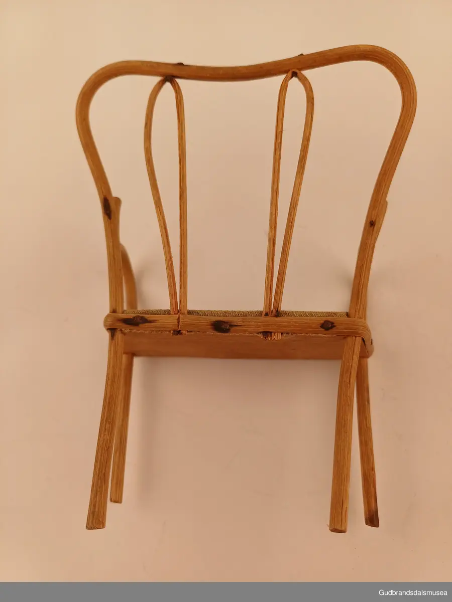 Leke sofa. En del av et sett med 2 stoler til
Buet rygg, spikret til setet med pedding som er lagt utenpå/rundt setekanten. Setet er av furu, trekt med stoff.
Bredde 10 cm
Høyde 14 cm