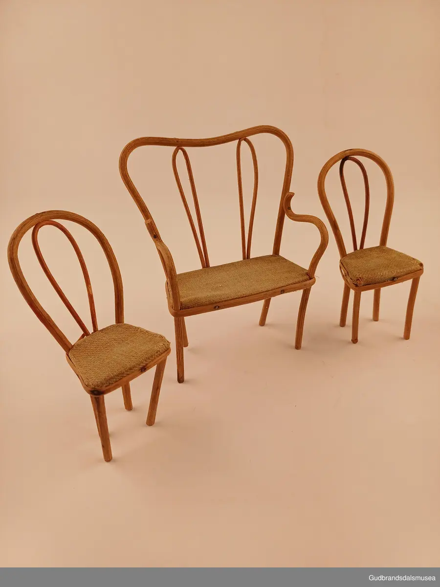 Leke sofa. En del av et sett med 2 stoler til
Buet rygg, spikret til setet med pedding som er lagt utenpå/rundt setekanten. Setet er av furu, trekt med stoff.
Bredde 10 cm
Høyde 14 cm