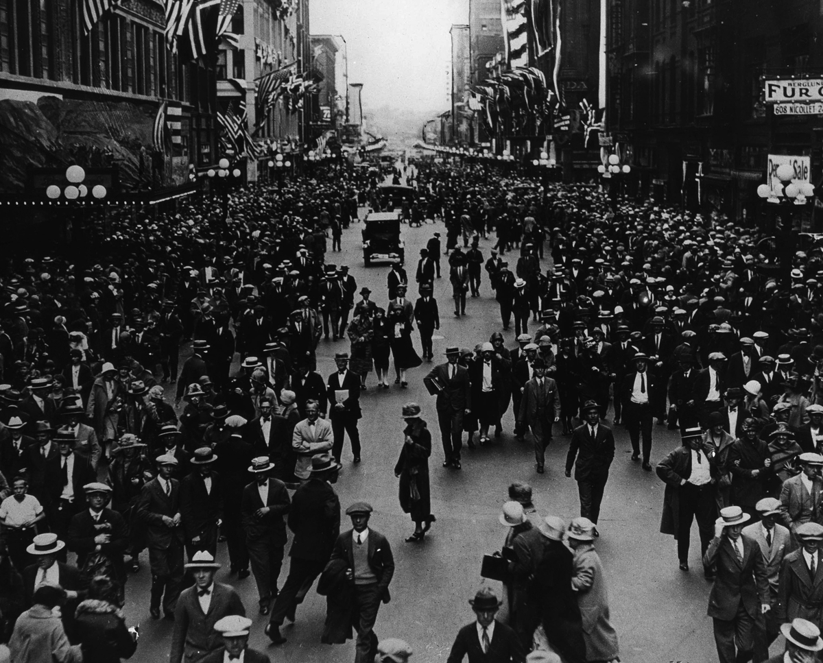 Folkemengde i en flaggpyntet bygate under Innvandrerjubileet i 1925.