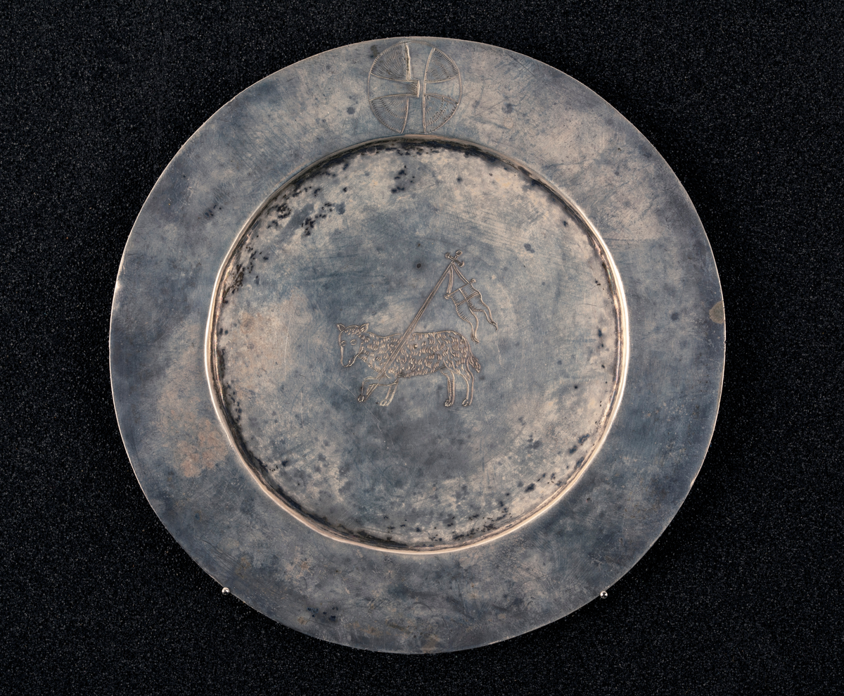 Fra protokoll: Skål av sølv med malteserkors og guds lam. Under bunnen gravert. Stemplet: se foto.