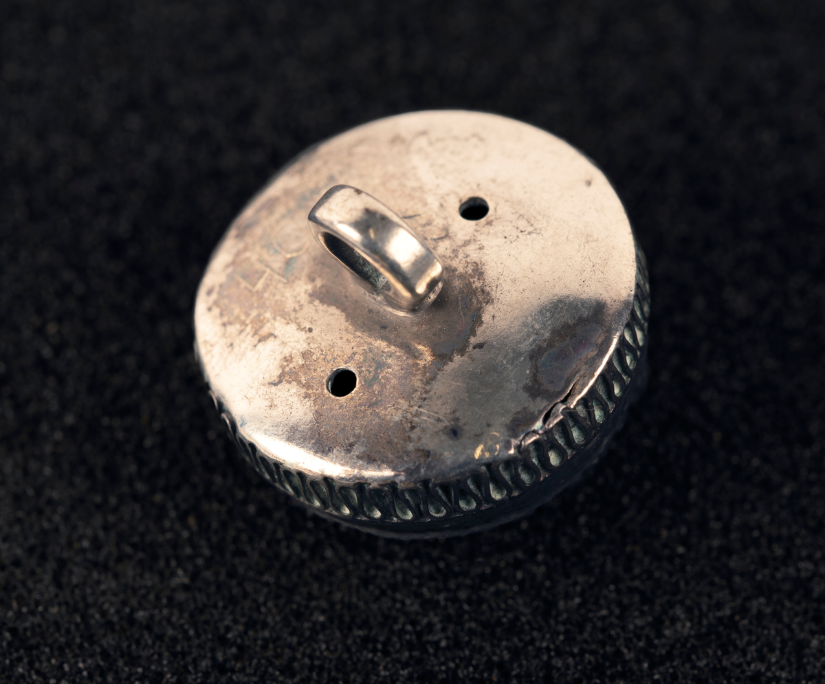 Øyeknapp av sølv, med filigranarbeider. Ingen stempel synlig.