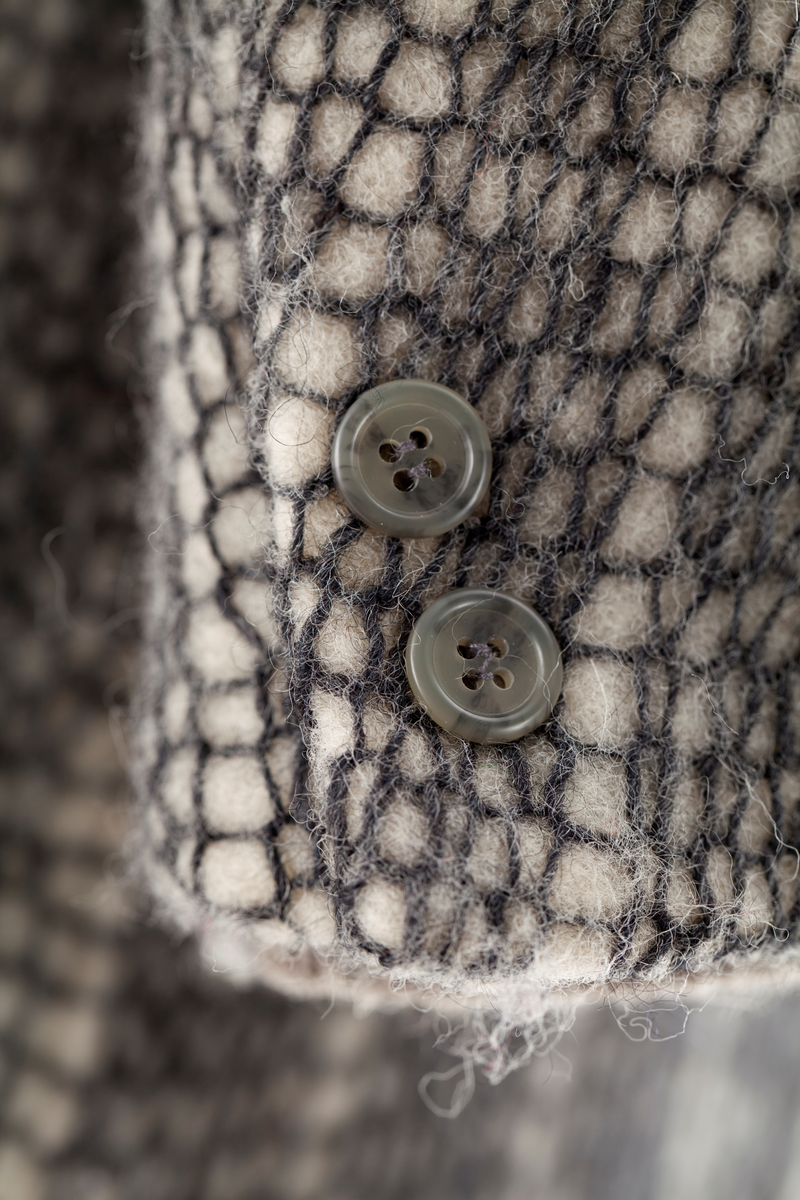 Dressjakke sydd av twool i koksgrå på hvit. Jakkens krage er strikket av tykt garn i ribbestrikk på tykke pinner i fargene (striper): oransje, gult, hvitt, lyseblått, rødt, gulbrunt og lysegrått.