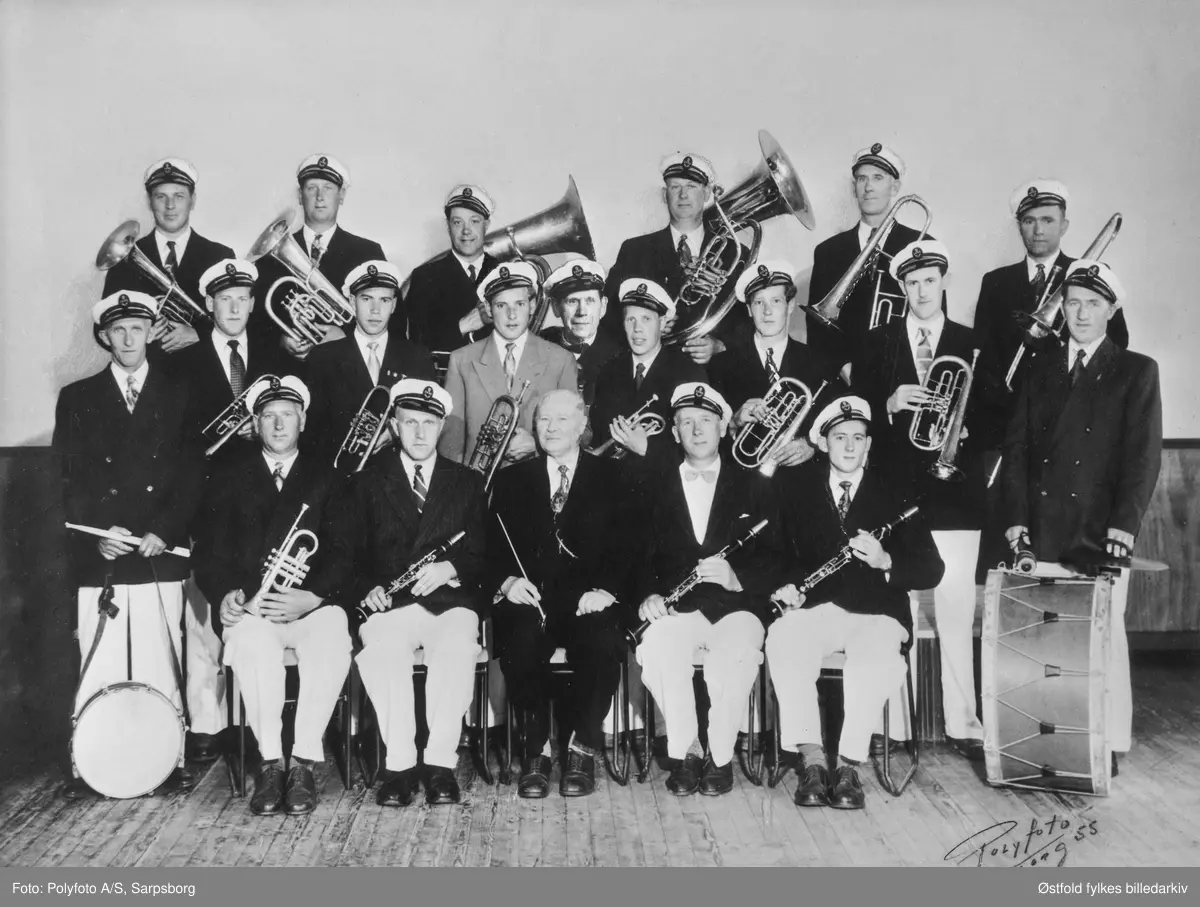 Musikkorpset "Ekko", Varteig, hos fotografen i Sarpsborg i 1955. Dirigent Karl Brende. Navneliste med plassering på fotokort.