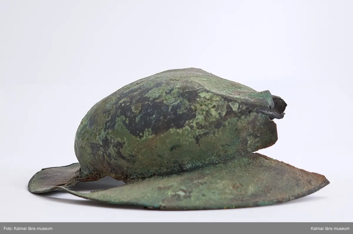 KLM 4911. Sköldbuckla, av brons. Den översta knoppen är av järn och överdragen av brons. En halvsfärisk nit. Sköldbucklan är i flera delar. Gravfynd tillsammans med KLM 4912-4915.