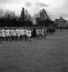 Gymnastikuppvisningen, 25/5 1941. 
En skara kvinnliga elever, klädda i gymnastikdräkt, håller på
att ställa upp på skolgården till Växjö Högre Allmänna Läroverk. 
I bakgrunden skymtar en av flyglarna till dåv. Växjö lasarett.