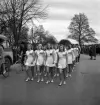 Gymnastikuppvisningen, 25/5 1941. 
En vitklädd gymnastiktrupp, bestående av kvinnliga gymnaster, marscherar fram längs Storgatan.