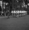 Gymnastikuppvisningen, 25/5 1941. 
Manliga gymnaster tågar in på Värendsvallen, med en uniformsklädd
herre i täten.