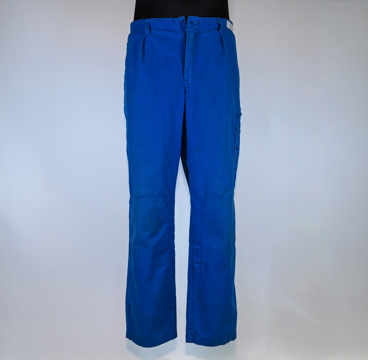 Byxa i blått tyg i modell arbetsbyxa. På båda byxbenen finns invändiga fickor för knäskydd. Sju öglor för livrem samt nio fickor varav en har lock med metallknapp. På vardera sida om byxlinningen sitter en kapp med tillhörande tygbit för att kunna reglera midjan. Storlek 58.

"Björnkläder" står skrivet på en fastsydd tygetikett på vänster bakficka. Texten är skriven i vita bokstäver och bakgrunden är blå.

"Björnkläder" står även skrivet på insidan längs med byxlinningen. Texten är skriven i mörkblåa bokstäver på blå bakgrund.

"Björnkläder / 58" står på fastsydd etikett vid inre byxlinning tillsammans med motiv av en björn. Texten är i gult på blå bakgrund.