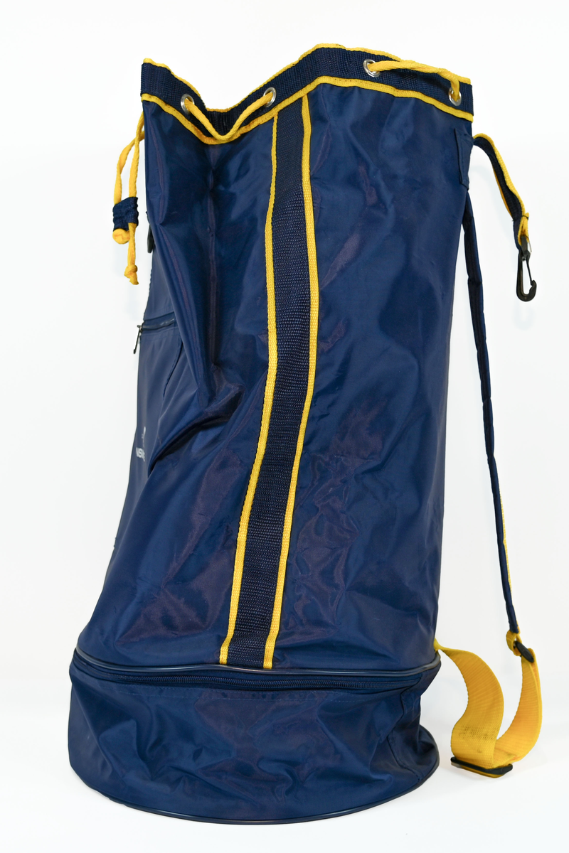 Mörkblå sjösäck med gula detaljer. På väskan står 'TRANSWEDE' och ett avbildat flygplan. Öppningen sitter upptill och går att stänga med ett gult rep samt en hake. Väskan går även att öppna från sidan genom en dragkedja. Det finns två fickor, en framtill samt en vid botten, båda med dragkedja.