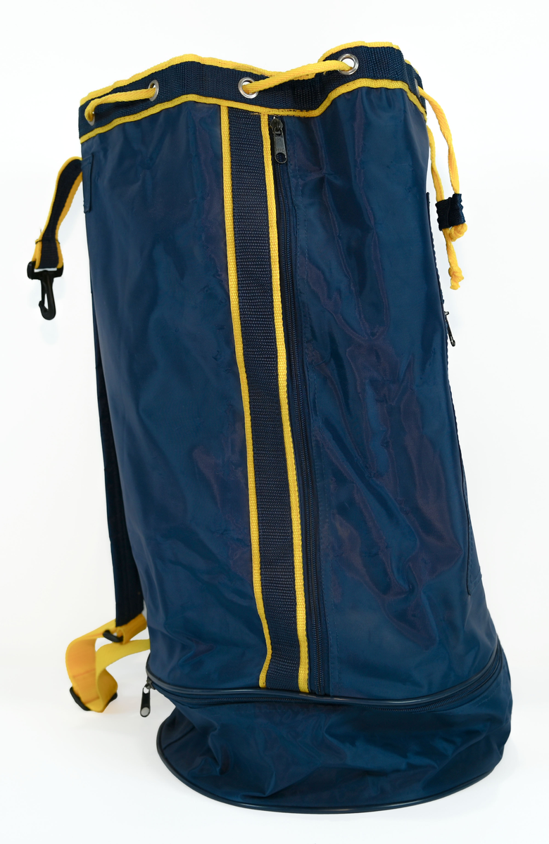 Mörkblå sjösäck med gula detaljer. På väskan står 'TRANSWEDE' och ett avbildat flygplan. Öppningen sitter upptill och går att stänga med ett gult rep samt en hake. Väskan går även att öppna från sidan genom en dragkedja. Det finns två fickor, en framtill samt en vid botten, båda med dragkedja.