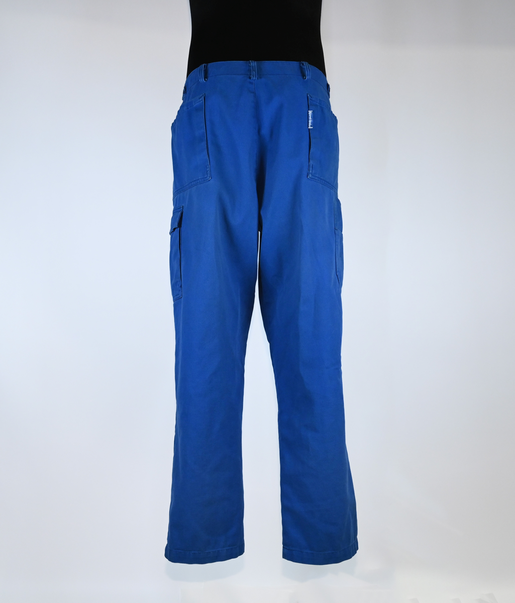 Byxa i blått tyg i modell arbetsbyxa. På båda byxbenen finns invändiga fickor för knäskydd. Sju öglor för livrem samt nio fickor varav en har lock med metallknapp. På vardera sida om byxlinningen sitter en kapp med tillhörande tygbit för att kunna reglera midjan. Storlek 58.

"Björnkläder" står skrivet på en fastsydd tygetikett på vänster bakficka. Texten är skriven i vita bokstäver och bakgrunden är blå.

"Björnkläder" står även skrivet på insidan längs med byxlinningen. Texten är skriven i mörkblåa bokstäver på blå bakgrund.

"Björnkläder / 58" står på fastsydd etikett vid inre byxlinning tillsammans med motiv av en björn. Texten är i gult på blå bakgrund.