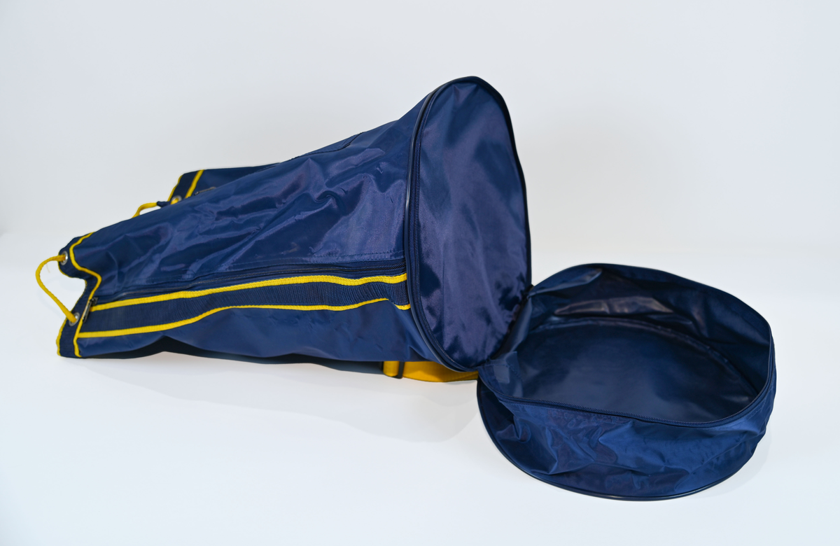 Mörkblå sjösäck med gula detaljer. På väskan står 'TRANSWEDE' och ett avbildat flygplan. Öppningen sitter upptill och går att stänga med ett gult rep samt en hake. Väskan går även att öppna från sidan genom en dragkedja. Det finns två fickor, en framtill samt en vid botten, båda med dragkedja.