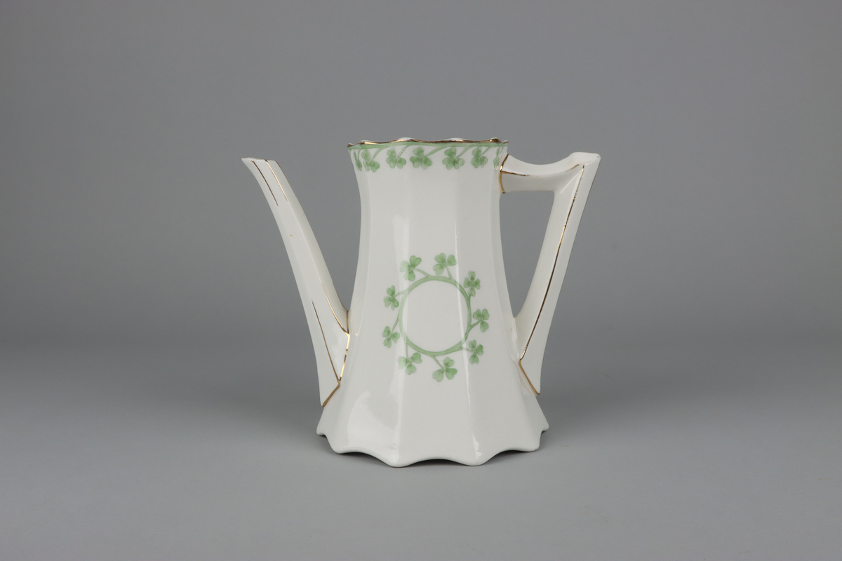 Kanna till kaffekanna med lock. Åttkantig klockad form som nedtill avslutas med vågig kant och upptill en något utvikt mynning.  Handtag och pip med en facetterad form. På kannan mitt fram och mitt bak krans med treklöverblad. På handtag och pip förgyllda smala lister. Under botten tryckt fabriksstämpel med Gustavsberg och servisnamn Gunnar.