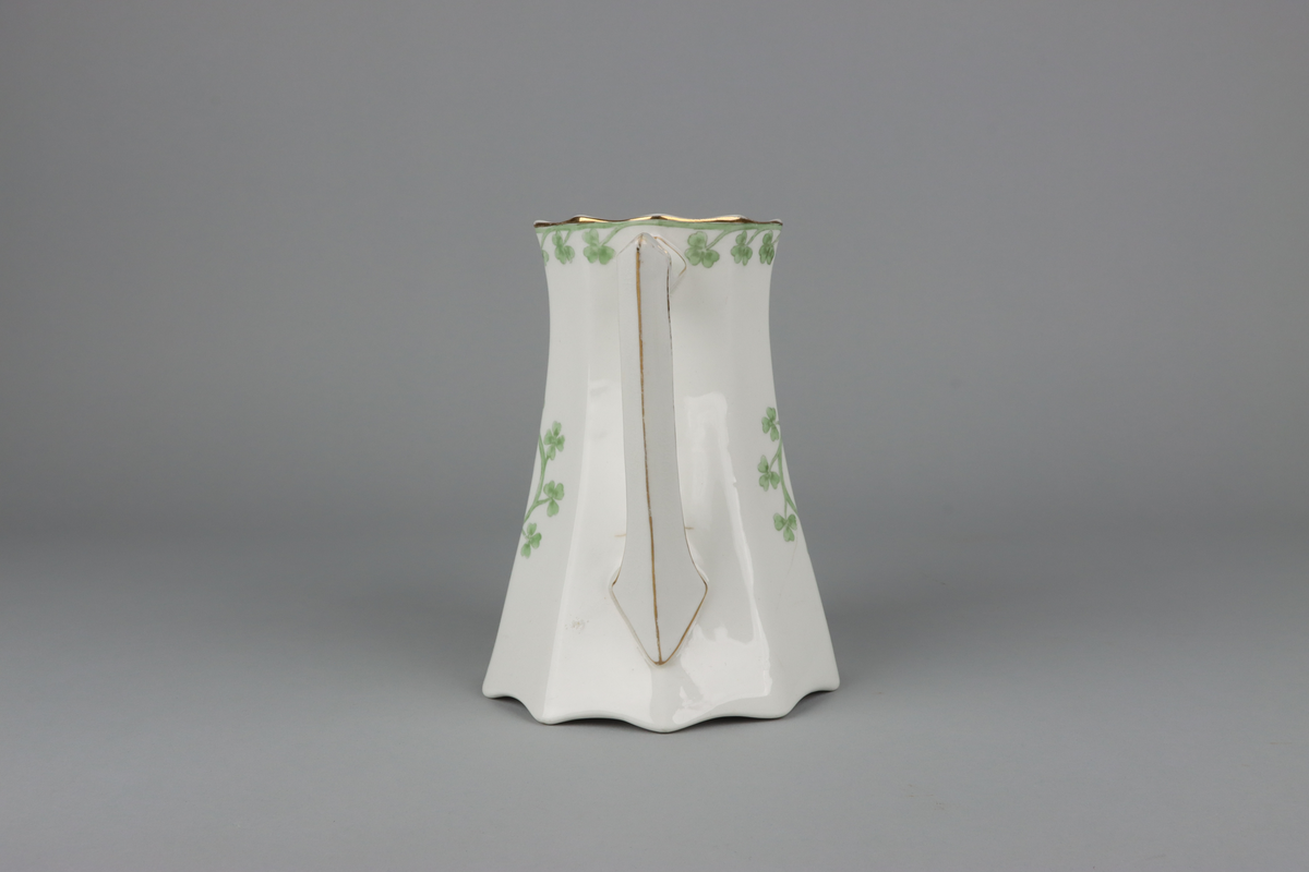 Kanna till kaffekanna med lock. Åttkantig klockad form som nedtill avslutas med vågig kant och upptill en något utvikt mynning.  Handtag och pip med en facetterad form. På kannan mitt fram och mitt bak krans med treklöverblad. På handtag och pip förgyllda smala lister. Under botten tryckt fabriksstämpel med Gustavsberg och servisnamn Gunnar.