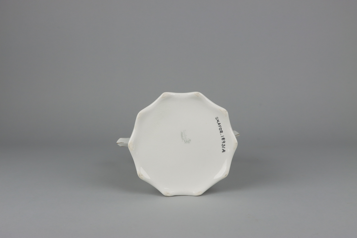 Kanna till kaffekanna med lock. Åttkantig klockad form som nedtill avslutas med vågig kant och upptill en något utvikt mynning.  Handtag och pip med en facetterad form. På kannan mitt fram och mitt bak krans med treklöverblad. På handtag och pip förgyllda smala lister. Under botten tryckt fabriksstämpel med Gustavsberg och servisnamn Gunnar.