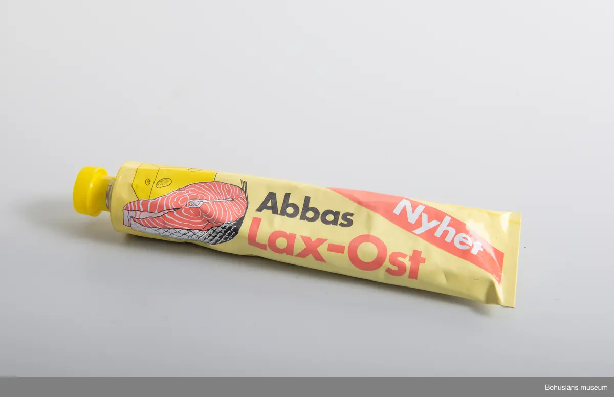 471 Tillverkningstid 1975-1985
410 Mått/Vikt !L 21, B 5,5CM
106 OCM *255,348
594 Landskap BOHUSLÄN
503 Kön MAN
394 Landskap BOHUSLÄN
601 Tub med tryckt dekor i gult,rosa,vitt och svart. Gjutet,gult skruvlock
603 Text;"ABBAS Lax-Ost. Nyhet."På baksidan innehållsförteckning
604 samt streckkod för prismärkning. Identisk med  UM 26816
605 Om givaren se UM 26667