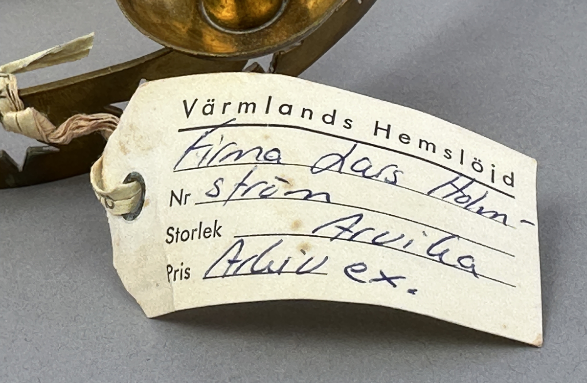 Ljusstake, "Luciakrona" för sex små julgransljus, gjord av mässingband med utstansat stjärnmönster. Ljushållarna är fastlödda på bandets högkant.