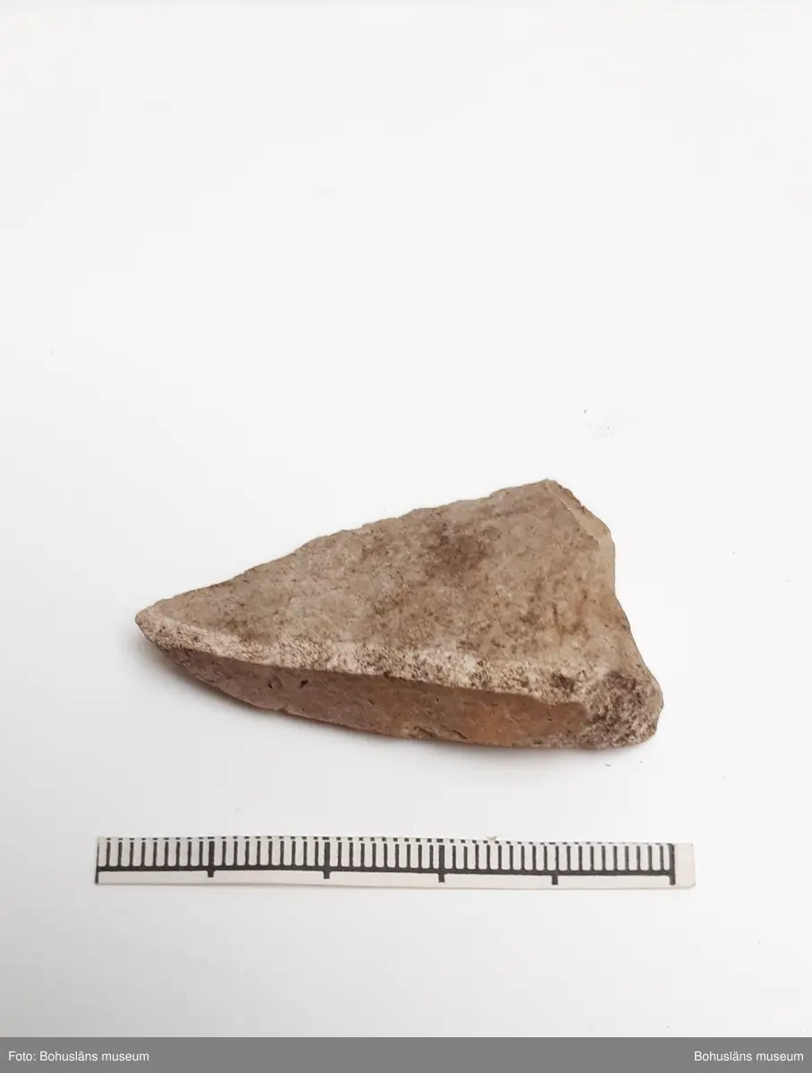 Tresidigt, spetsigt avslag med retusch längs en sida.

Landskap: Bohuslän