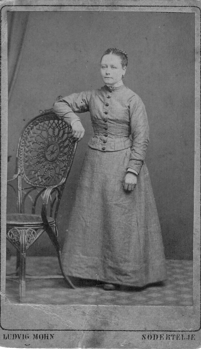 Anna Lovisa Andersson född 1859 vid Torsättra. Kortet är från 1877 och Lovisa bodde vid Torsättra och flyttade 1880 till Kärr i Turinge som piga och sedan till Nykvarns herrgård där hon tjänade hos förvaltare Cedervall med familj. Cedervall var representant i Turinge för Dalkarlshyttan som ägde Nykvarn och Ströpsta med underliggande arrendegårdar och torp.
Lovisa flyttade med familjen Cedervall till Södertälje 1898
Kortet kanske är taget för att sändas till Lovisas faster och kusiner som utvandrat till Brasilien 1868
Lovisa blev drygt 100 år