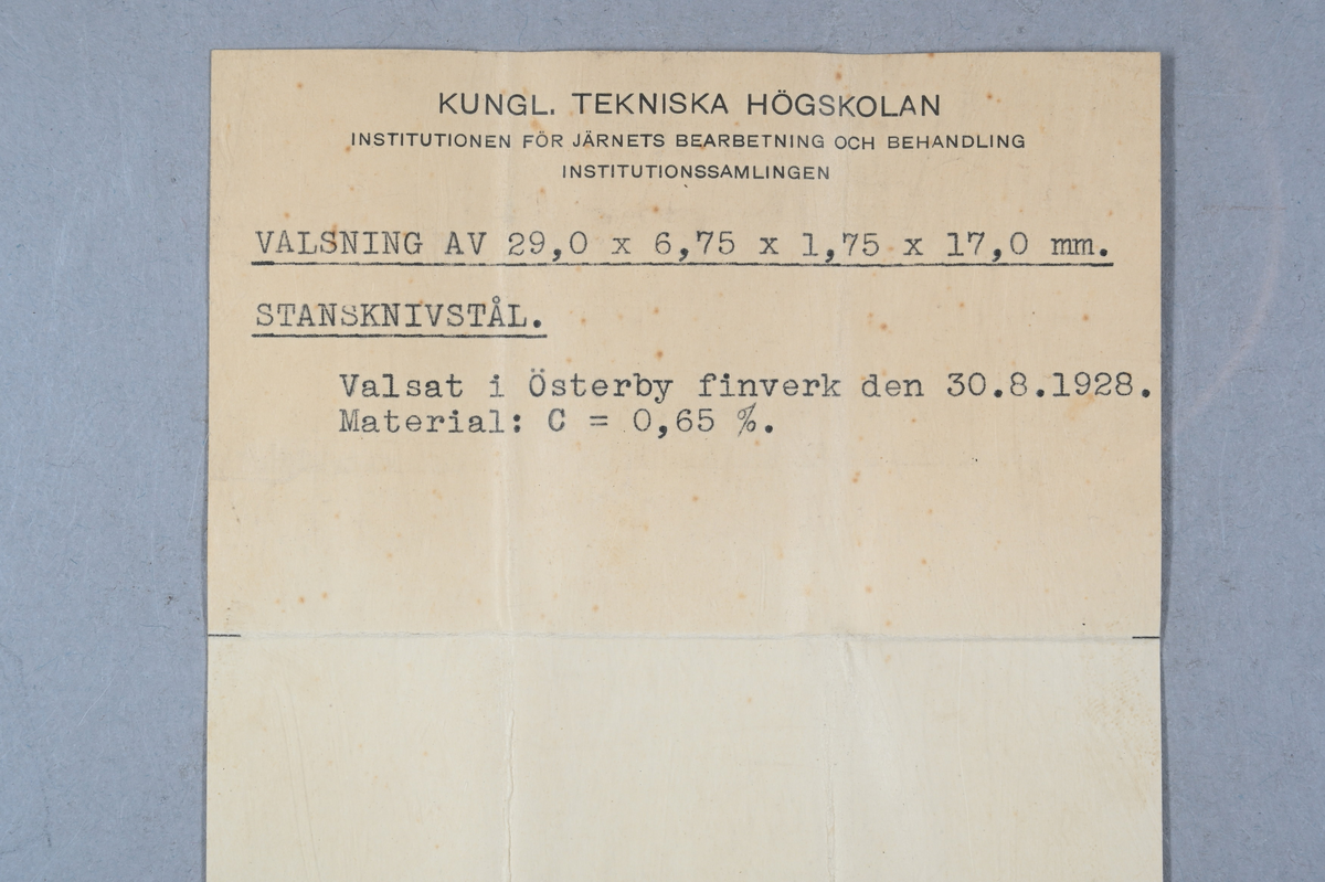 Sju prov på valsning av stansknivstål. Tillhörande lapp med notering: "Valsning av 29,0 x 6,75 x 1,75 x 17,0 mm. Stanknivstål. Valsat i Österby finverk den 30. 8. 1928. Material: C = 0,65 %."