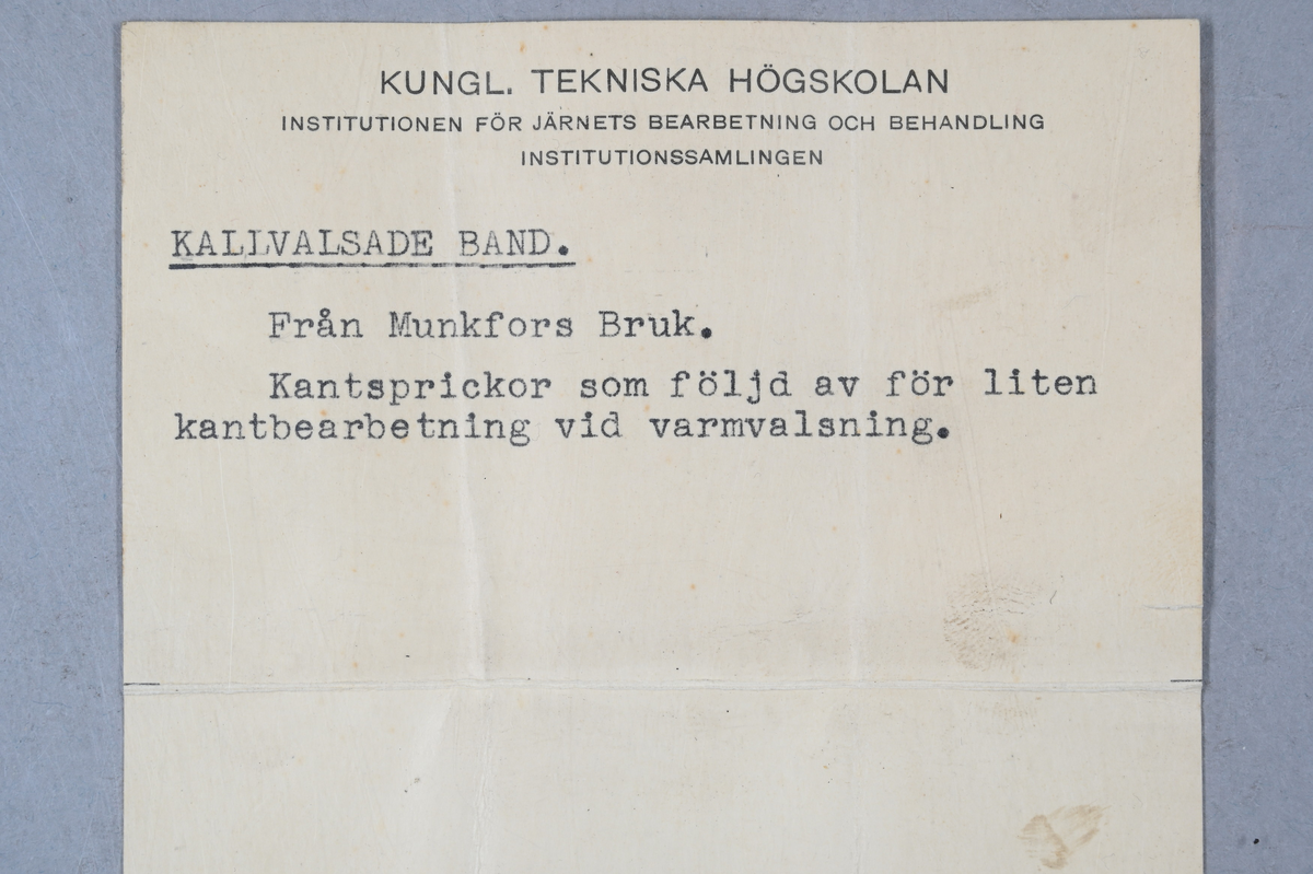 Två prover på kallvalsade band. Tillhörande lapp med notering: "Kallvalsade band. Från Munkfors Bruk. Kantsprickor som följd av för liten kantbearbetning vid varmvalsning."