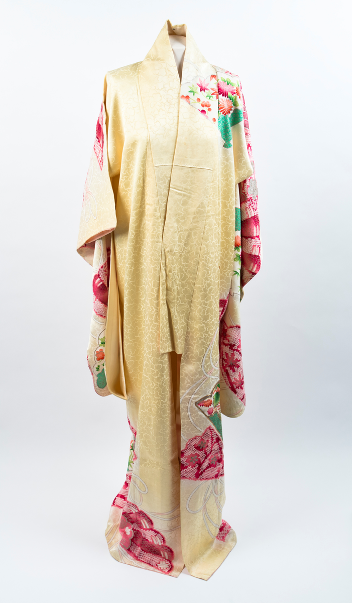 Kimono i gul silke med innvevde peoner og mønster med blomster og blader i rødt, rosa, grønt, sjøgrønt, gull og sølv. Kimonoen er fôret med kremfarget silke, nederste del er farget rosa slik at det er en jevn overgang fra rosa til kremfarget.