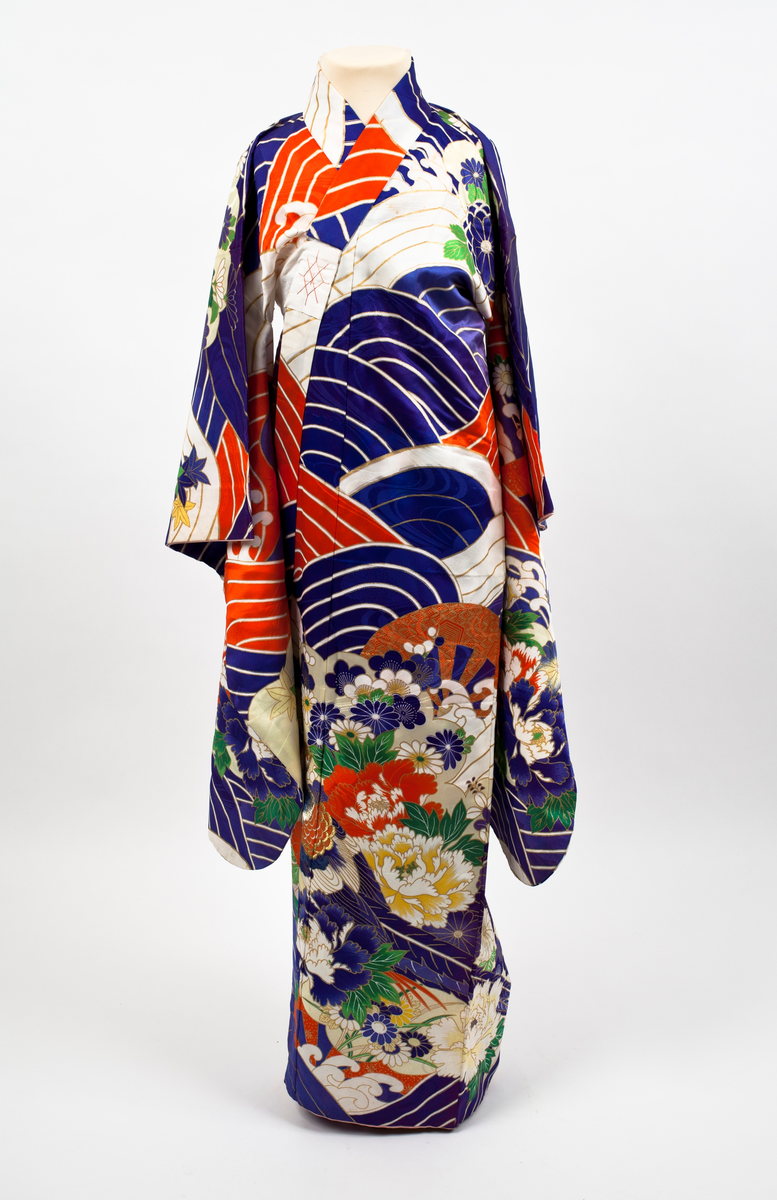 Kimono i mønstret silke. Stort bølgemønster i blått, hvitt og rødt med gullfargede kanter. I kimonoens nedre del og på ermene blomstermønster med krysantemer og peoner mot gullfarget bunn. Påsydde hvite bånd som kan knytes.