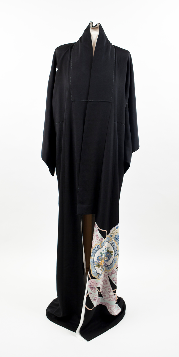 Kimono i svart silke med et kontinuerlig mønster plassert diagonalt på den nedre delen av plagget. Motivet er orientalsk, blomsterdekorert porselen med konturer fremhevet av påsydde gull-lisser, samt hvite bånd med rosa blomster og flettede snorer imellom porselenet. Kimonoen har små ornamenter (komon) plassert i nakken, på skuldre og ermer.