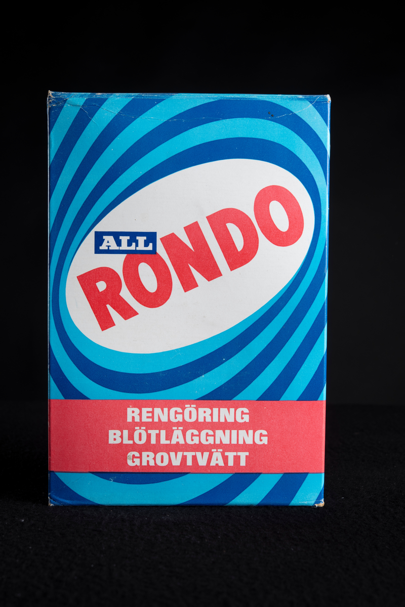 Tvättmedelsförpackning i blått vitt och rött, av papp. Tom på innehåll, eventuellt återförsluten med lim.