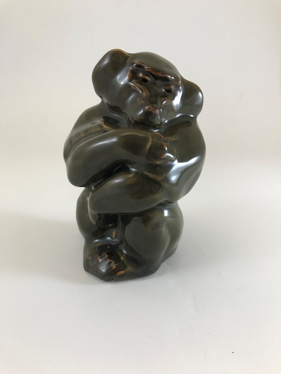 Knud Kyhn, skulptur apa (mantelbabianhane), mörk olivgrön Olivinglasyr. Unik signatur. Tillverkning: Den Kongelige Porcelainsfabrik, Köpenhamn, Danmark.