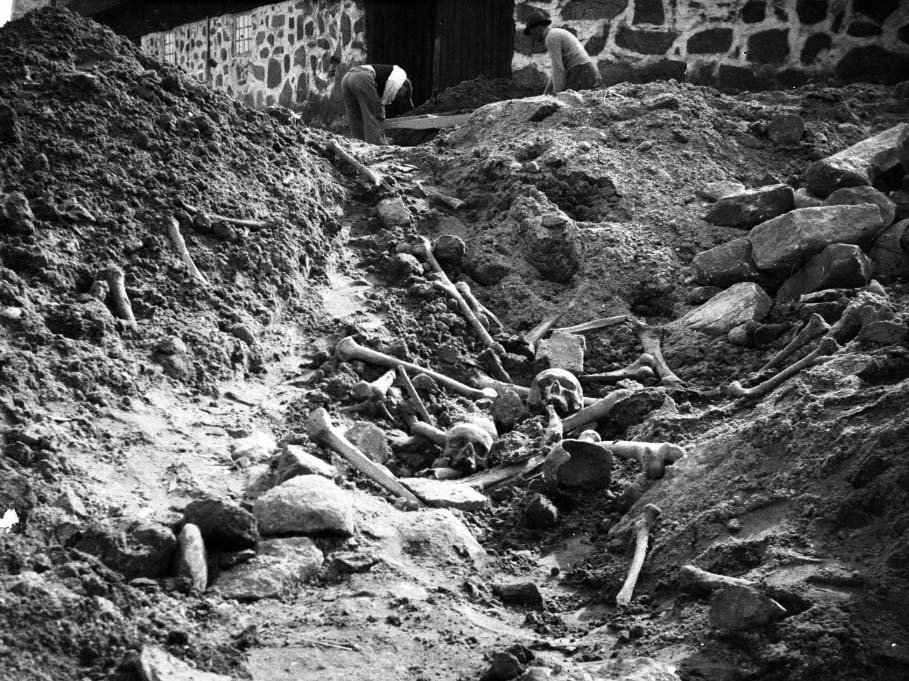 Arkeologisk utgrävning vid Lindhovs gård. 124 gravar grävdes ut under kyrkan år 1937. Ett schakt med skelettdelar. Fotografen är okänd. Två bilder.
