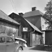 In på gården till Klostergatan 21 i Linköping. Notera att den enkla verkstadslokalen fått särdeles vackra dörrar monterade i gaveln. Nygotik i forn prakt. Foto 1965.