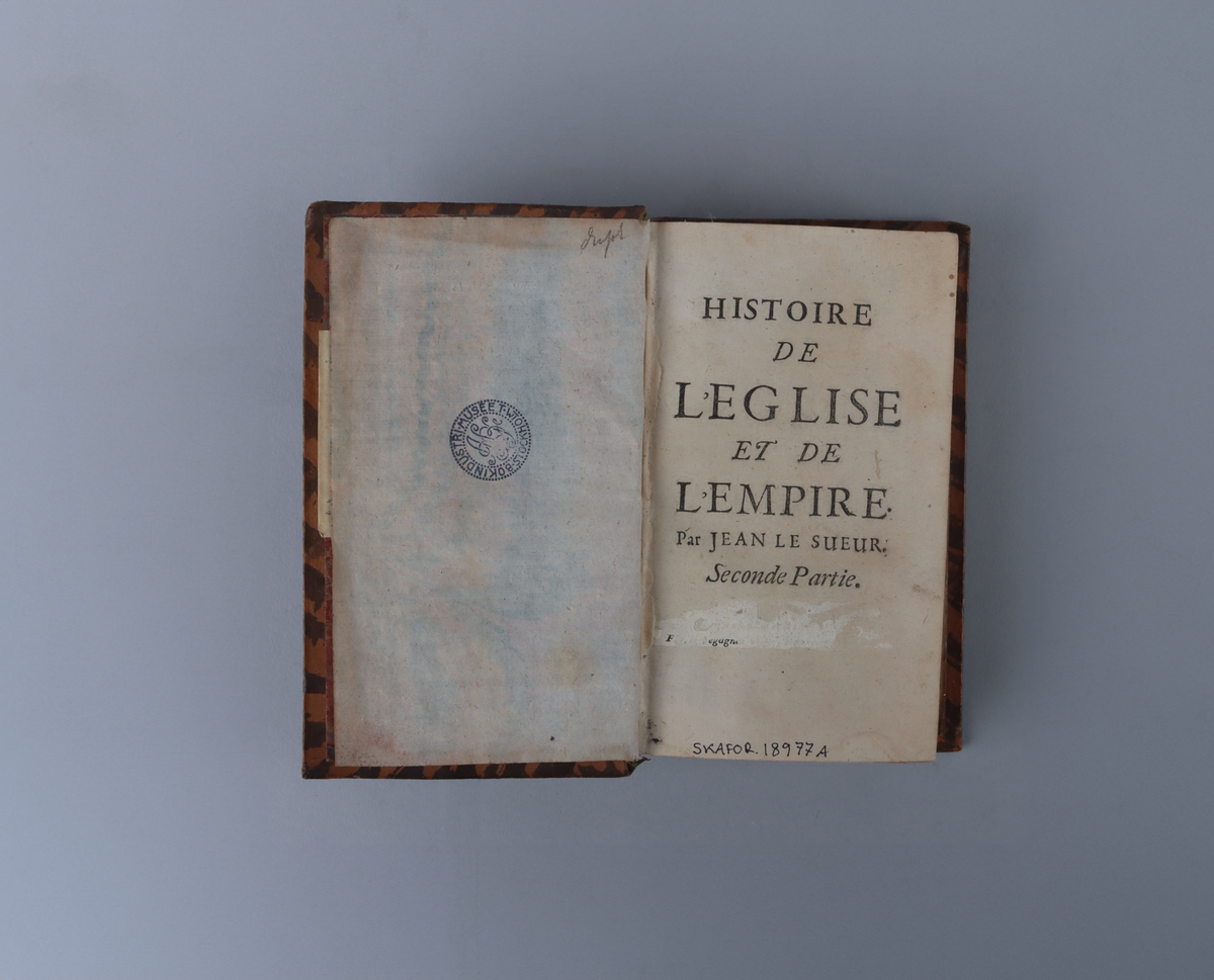 Bok med marmorerat skinnband och fem upphöjda bind, rikt guldornerad rygg, mörkbrun titeletikett av glättad papp, och stänkta snitt. Titelsida med  " Historie de l`eglise et de l´empire, par Jean Le Sueur, Trosieme partie".