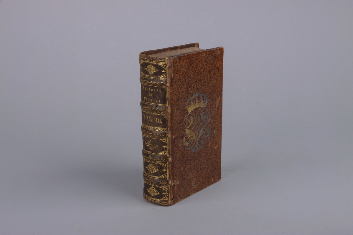 Bok med marmorerat skinnband och fem upphöjda bind, rikt guldornerad rygg, mörkbrun titeletikett av glättad papp och stänkta snitt. Titelsida med  " Historie de l`eglise et de l´empire, par Jean Le Sueur, Second partie".