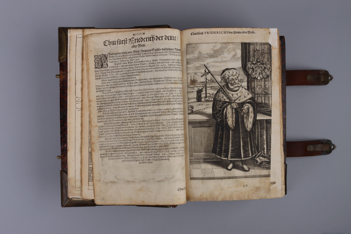 Bibel, marmorerat skinnband med upphöjda bind, dekorerad rygg. På framsida beslag i genombruten mässing med olika apostlar mitt på Moses med stentavlor. Omtag och lås med Karl XII monogram. Bibeln rymmer flertalet planscher och porträtt samt utvik med kartor.