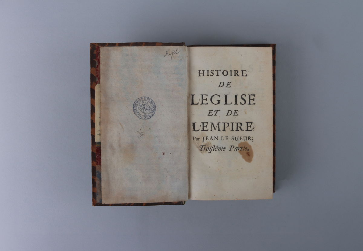 Bok med marmorerat skinnband och fem upphöjda bind, rikt guldornerad rygg, mörkbrun titeletikett av glättad papp och stänkta snitt. Titelsida med  " Historie de l`eglise et de l´empire, par Jean Le Sueur, Second partie".