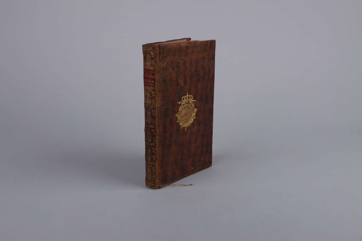 Bok, marmorerad skinnband, med guldornerad rygg, mörkröd titeletikett av glättad papp och röda snitt. På framsida kungligt monogram i guld, Gustav den tredje, På insida av pärm exlibris från Christian Hammer. Titelsida med "Histoire raisonnée des opérations militaires et politiques de la dernière guerre, suivie d'observations sur la révolution qui est arriv´ée dans les mœurs & sur celle qui est sur le point d'arriver dans la constitution d'Angleterre". par M.Joly De St. Valier, Lieutenant - Colonel d´Infanterie, A Liége, Et  fe trouve che les principaux Libiraires de Í´Europe".