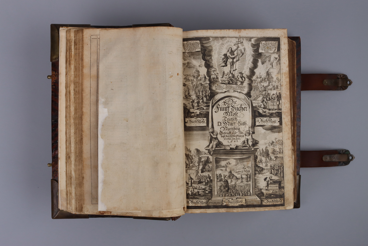 Bibel, marmorerat skinnband med upphöjda bind, dekorerad rygg. På framsida beslag i genombruten mässing med olika apostlar mitt på Moses med stentavlor. Omtag och lås med Karl XII monogram. Bibeln rymmer flertalet planscher och porträtt samt utvik med kartor.