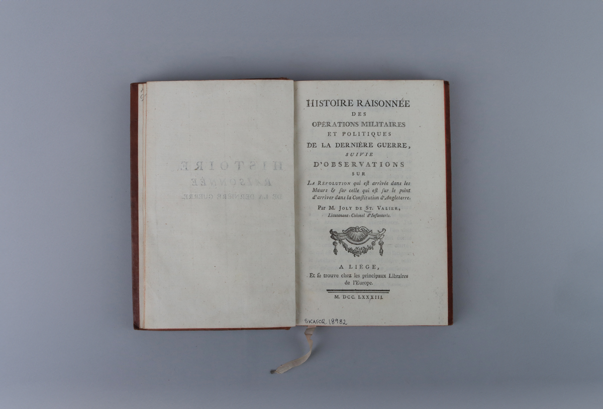 Bok, marmorerad skinnband, med guldornerad rygg, mörkröd titeletikett av glättad papp och röda snitt. På framsida kungligt monogram i guld, Gustav den tredje, På insida av pärm exlibris från Christian Hammer. Titelsida med "Histoire raisonnée des opérations militaires et politiques de la dernière guerre, suivie d'observations sur la révolution qui est arriv´ée dans les mœurs & sur celle qui est sur le point d'arriver dans la constitution d'Angleterre". par M.Joly De St. Valier, Lieutenant - Colonel d´Infanterie, A Liége, Et  fe trouve che les principaux Libiraires de Í´Europe".